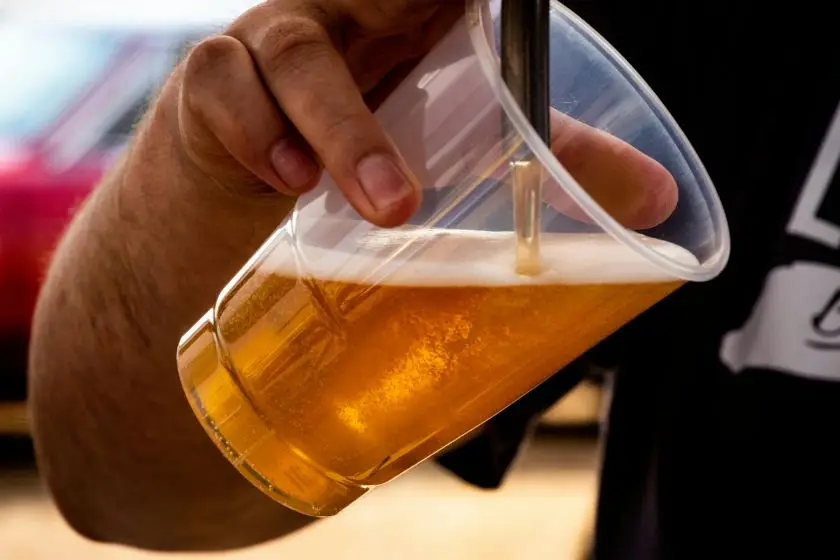 Person Pouring Beer on Clear Cup
