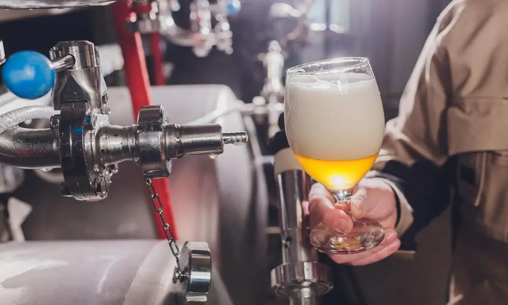 Man inspecting a beer tap and tank valve during equipment maintenance.