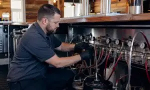 Technician repairing a draft beer system under a bar counter