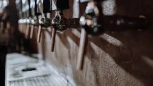 Close-up of beer taps in a bar with warm lighting and texture, representing clean draft beer systems.
