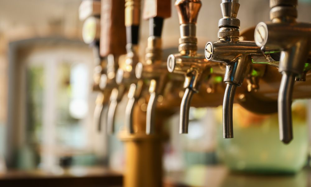 A close-up, shallow depth of field shot of a row of polished brass and stainless steel beer taps