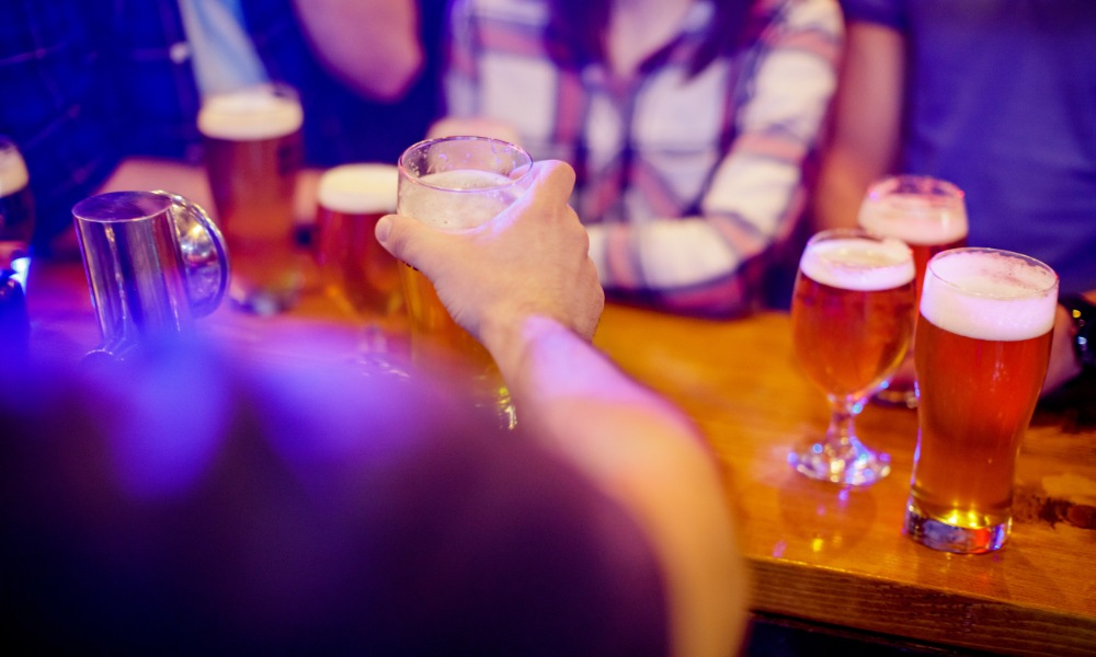 reaching for a beer glass on a wooden bar counter