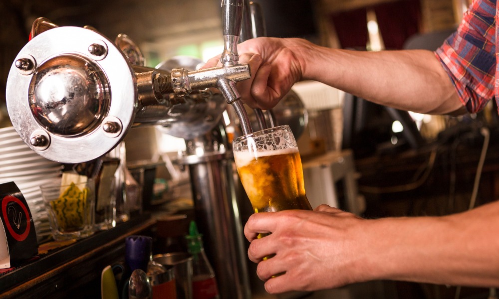 A bartender pouring a glass of draft beer 