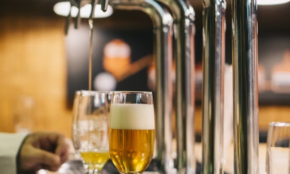 A thin stream of beer pouring from a chrome tap