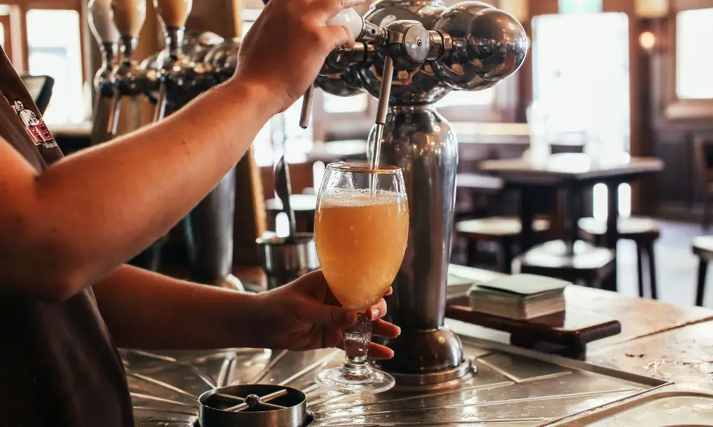 Bartender skillfully pouring a fresh draft beer at a lively bar counter.