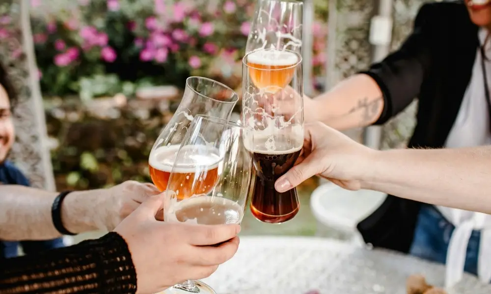 group of friends laughing together at a bar while holding beers