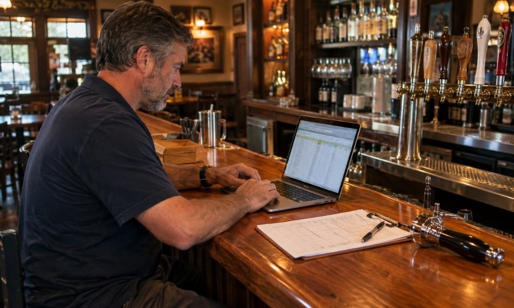 using a laptop alongside a clipboard with a spreadsheet
